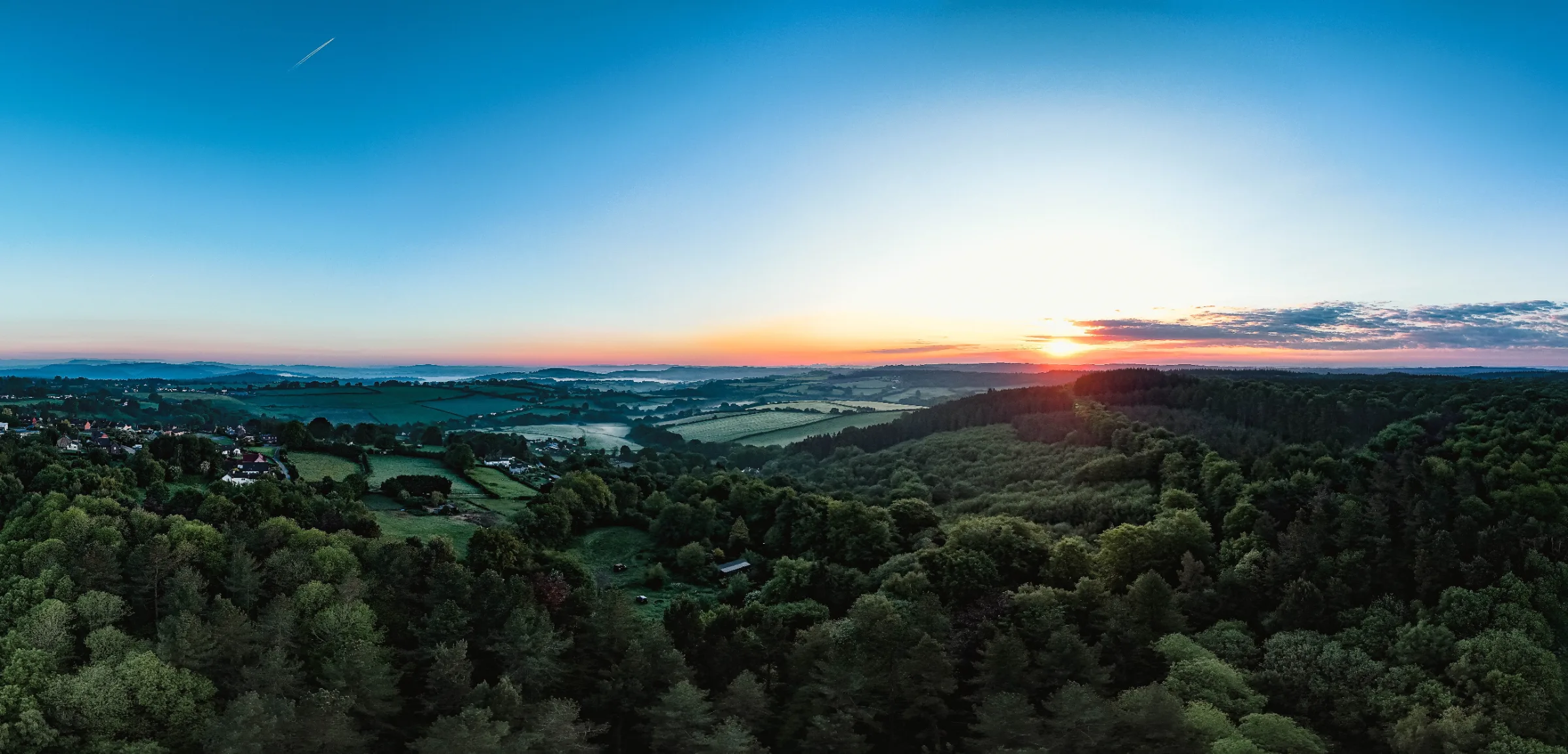 Panoramic sunset over wooded border countryside and distant hills